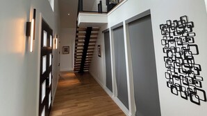 A modern interior with a wooden floor, a staircase, and a ceiling light fixture.
