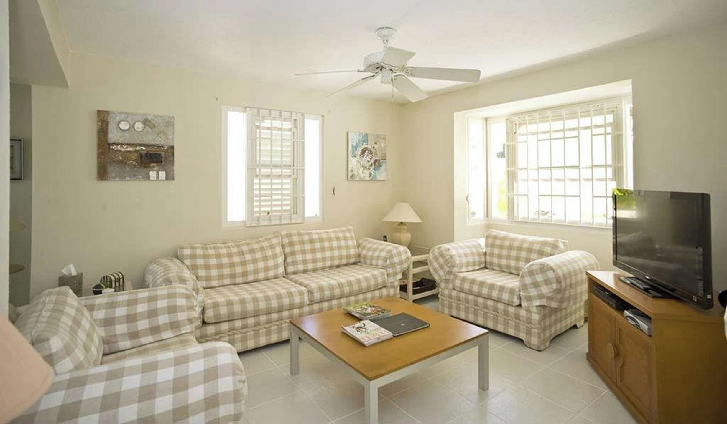 A living room with a sofa set, a coffee table, a TV, and a ceiling fan.