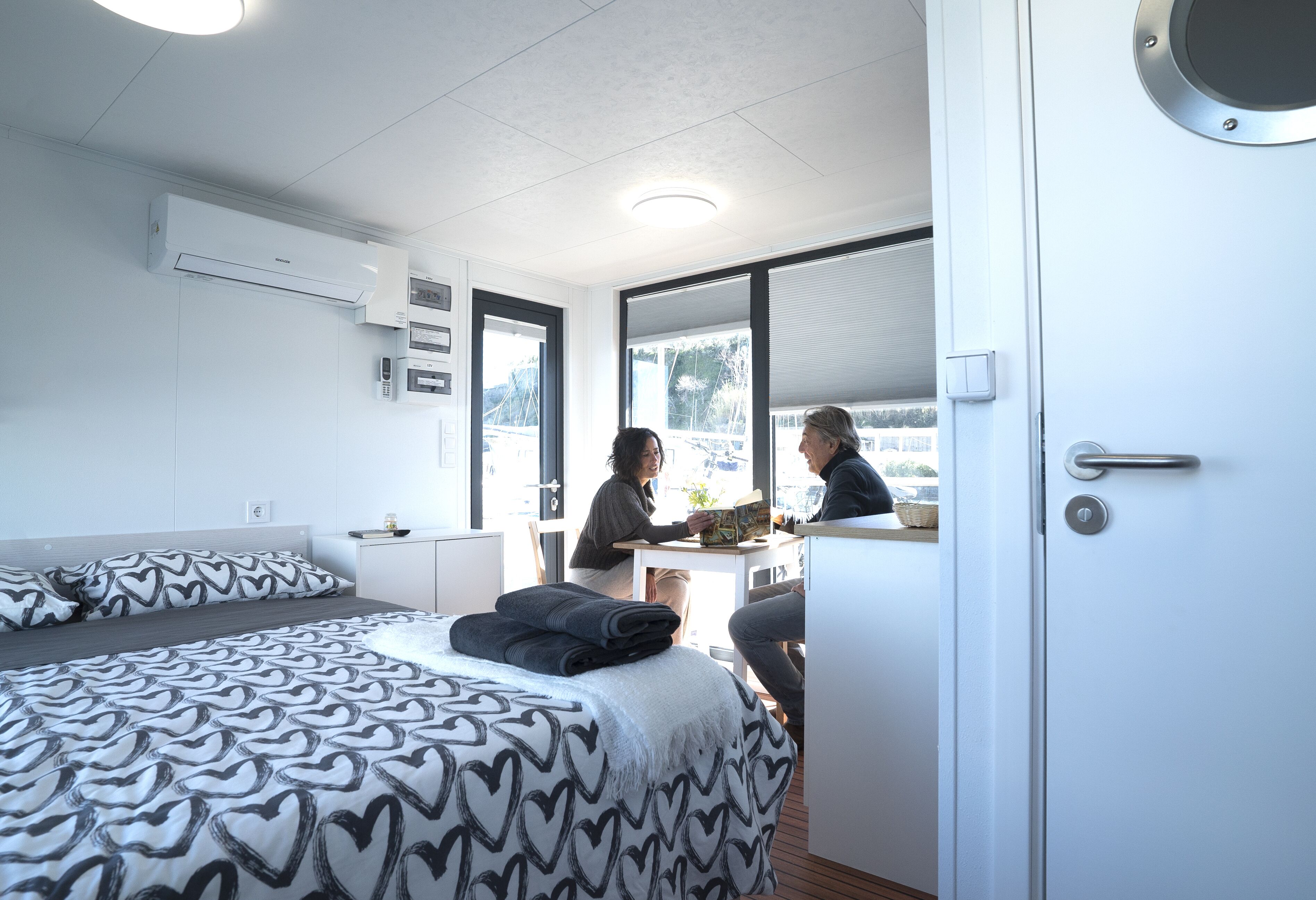 A modern hotel room with a bed, a desk, and a window with a view of the outdoors.