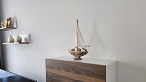 Moderni huone, jossa on puinen kaappi ja sen päällä pieni purjelaivamalli.