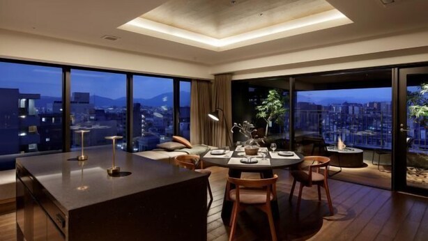 A modern dining area with a central island, large windows offering city views, and a cozy seating arrangement. - HIDEOUT (Kyoto)