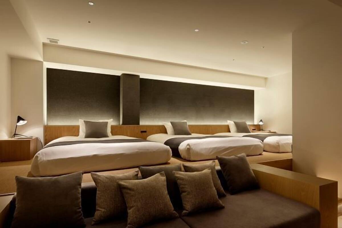 A modern hotel room with a large bed, a sofa, and a desk.