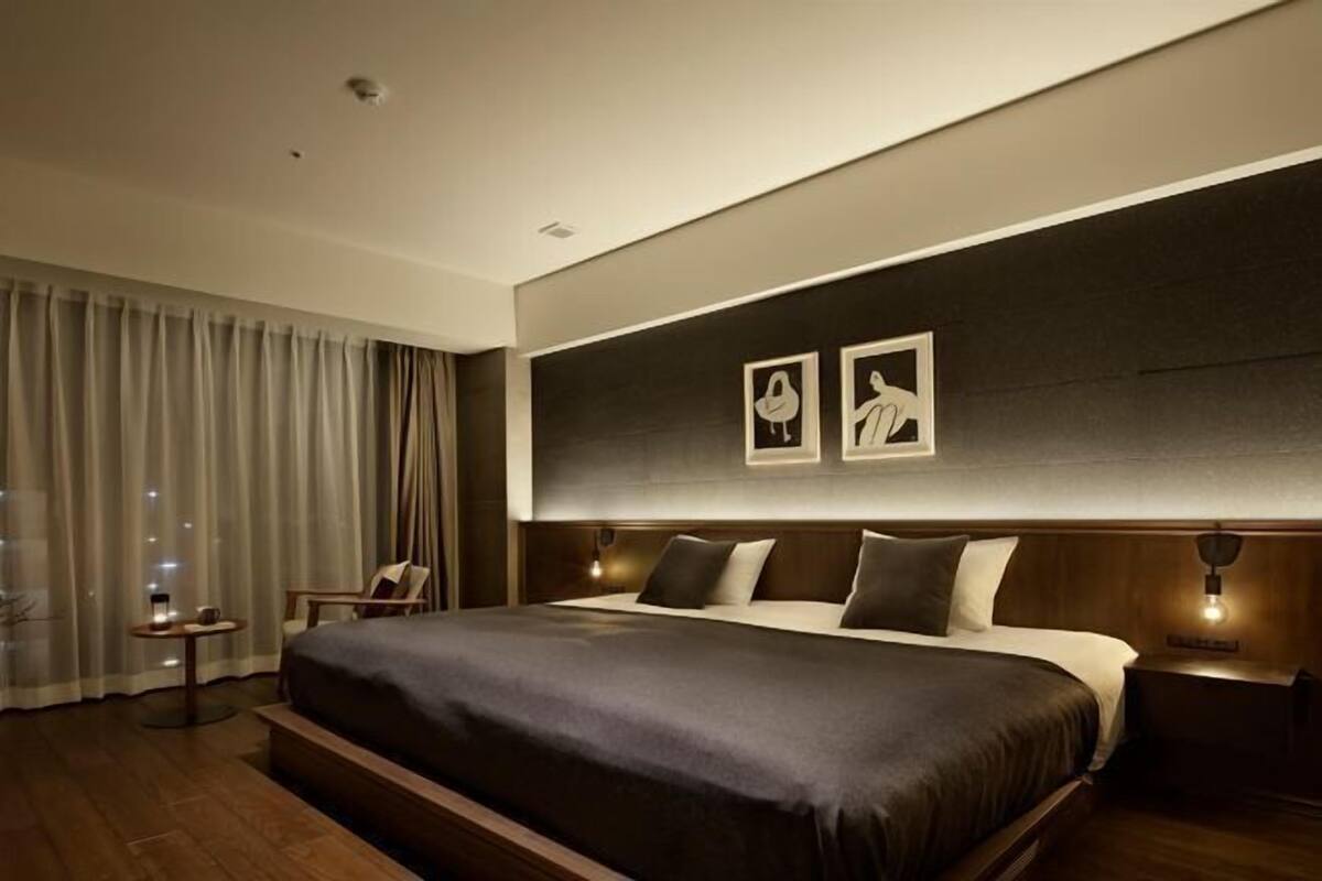 A modern hotel room with a large bed, a small table, and a chair.