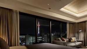 A modern hotel room with a large bed, a sofa, and a view of a cityscape at night. - HIDEOUT (Kyoto)