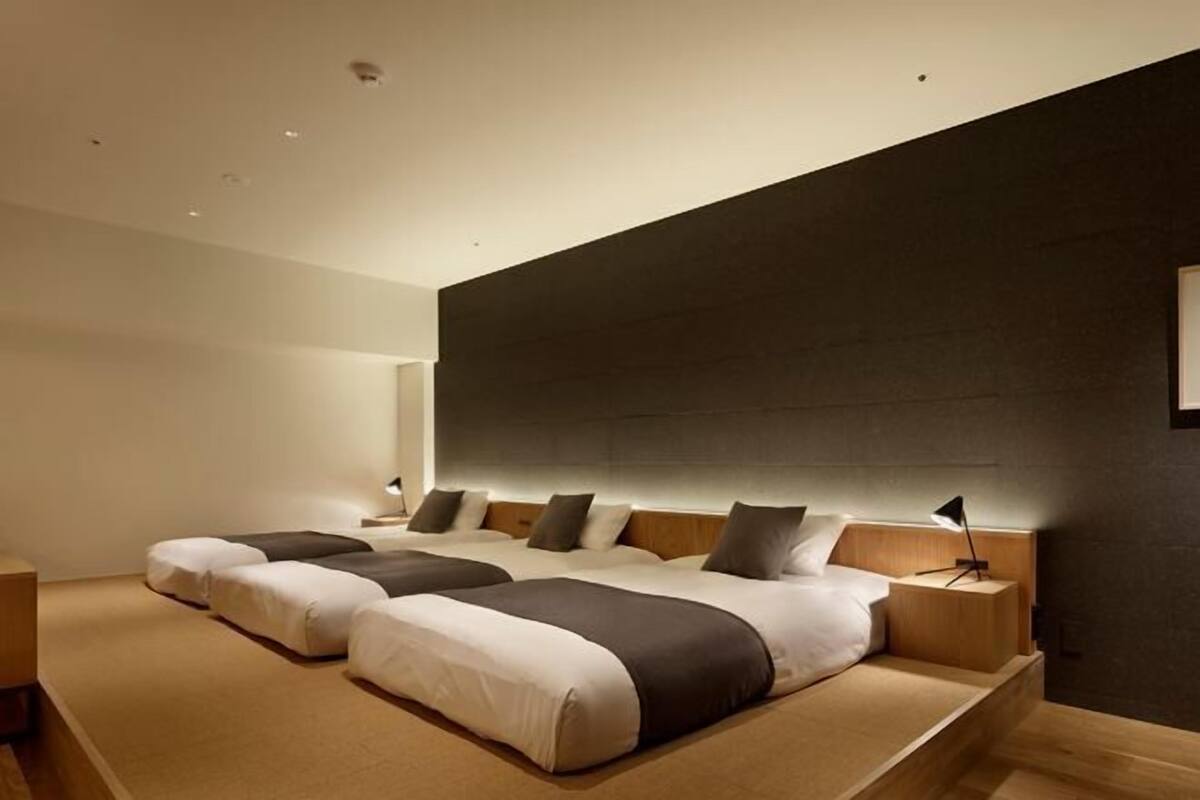A modern hotel room with a large bed, bedside tables, and a dark accent wall.