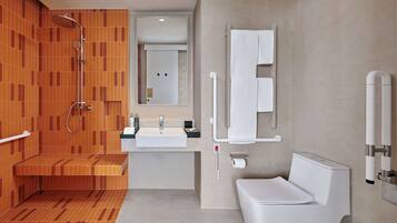 A modern bathroom with a shower, sink, toilet, and a towel rack.