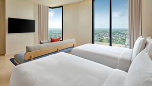 A modern hotel room with two beds, a flat-screen TV, large windows, and a city view. - Hilton Garden Inn Rayong (Rayong)