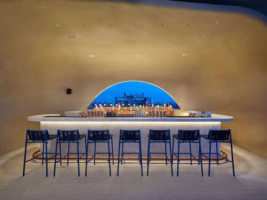 Un bar con una barra curva y un ventanal semicircular.