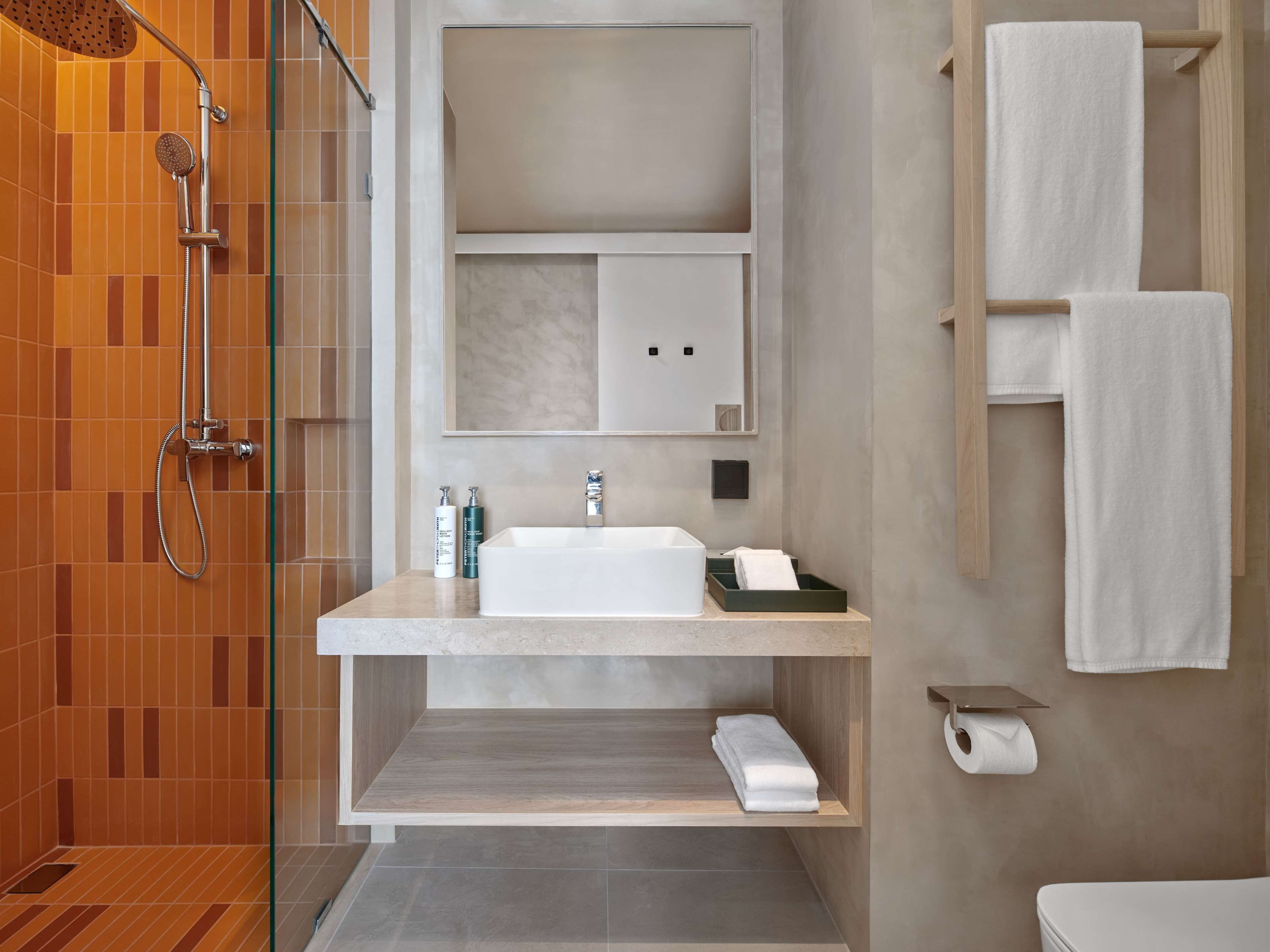 Un baño moderno con ducha, lavamanos e inodoro.