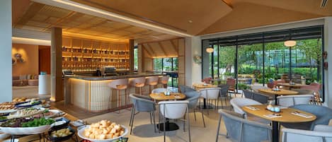 A modern dining area with a bar, seating, and a variety of food displays.