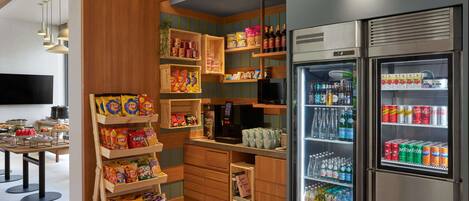A modern kitchen with wooden cabinetry, a built-in refrigerator stocked with beverages, and a variety of snacks and condiments on shelves.