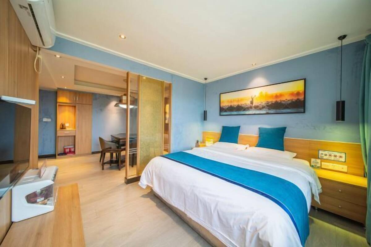 Una habitación de hotel con una cama, una mesita de noche y un cuadro en la pared.