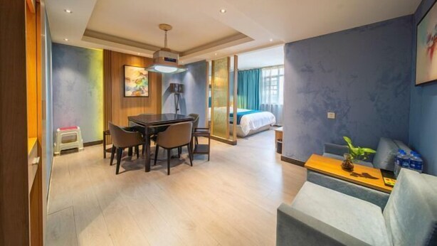 Ein Hotelzimmer mit Essbereich, einer Couch, einem Bett und einem großen Fenster.