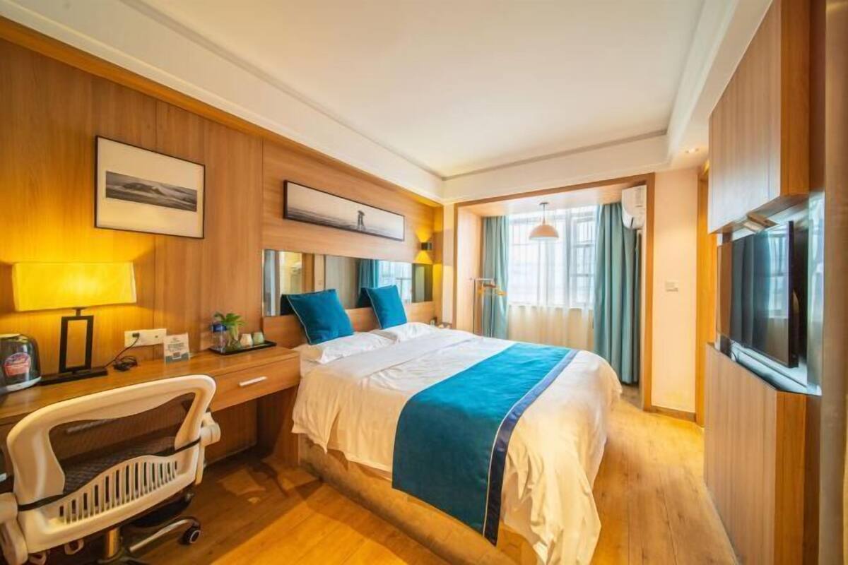 Una habitación de hotel con cama, mesita de noche, lámpara, silla y televisor.