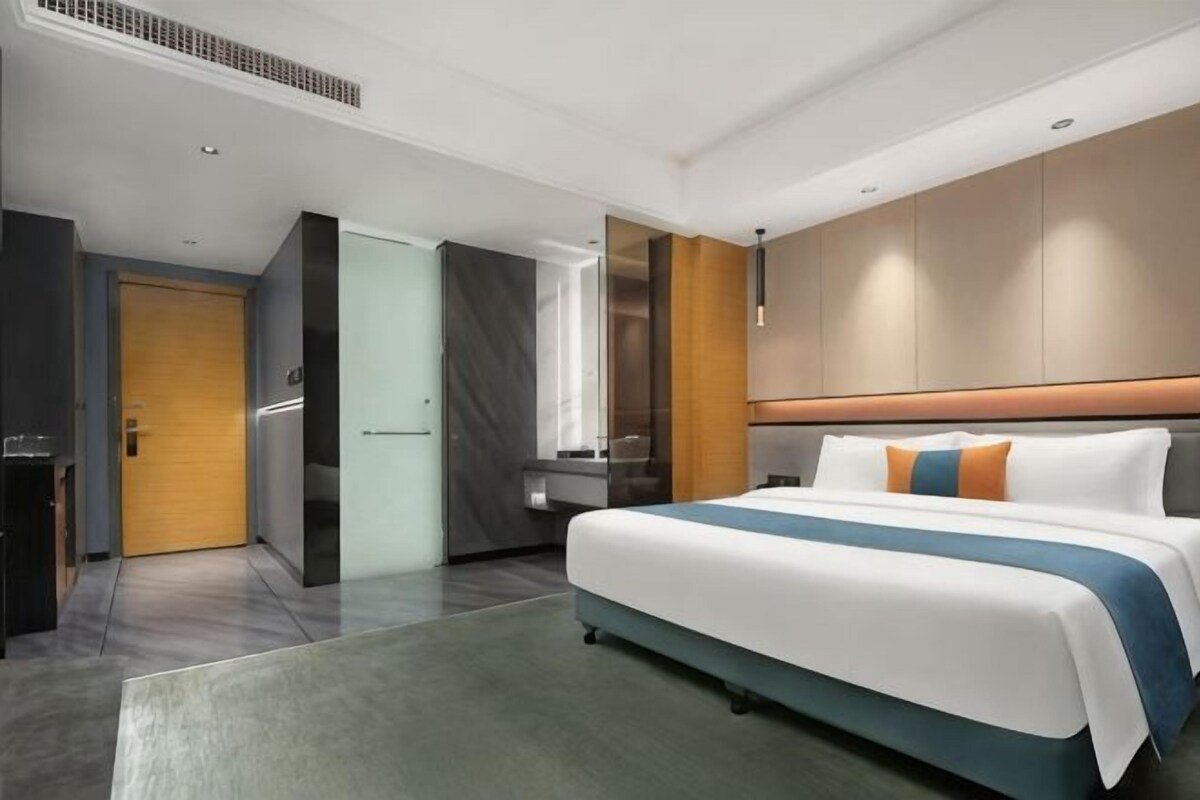 Una habitación de hotel moderna con una cama grande, un escritorio y un armario.