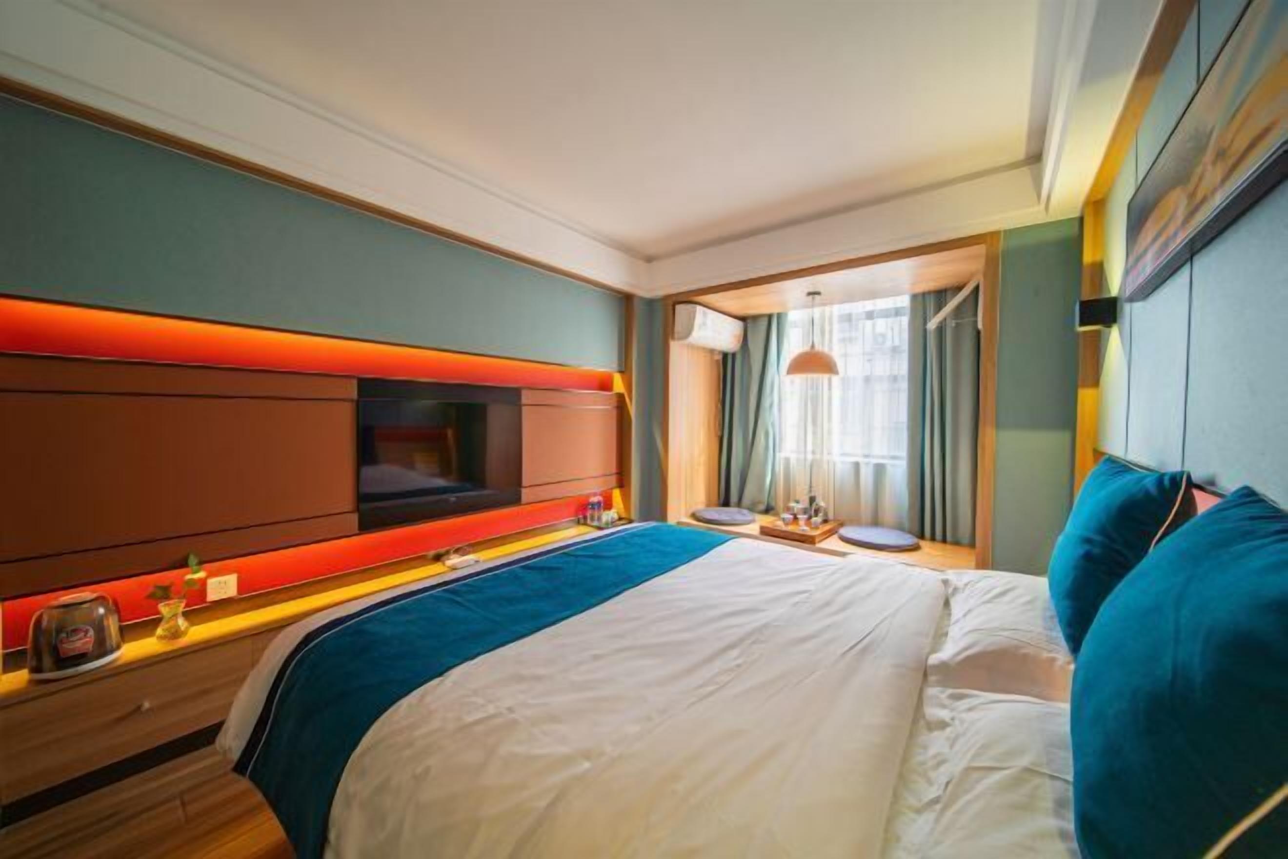 A hotel room with a large bed, a TV, a bedside table, and a window with curtains.