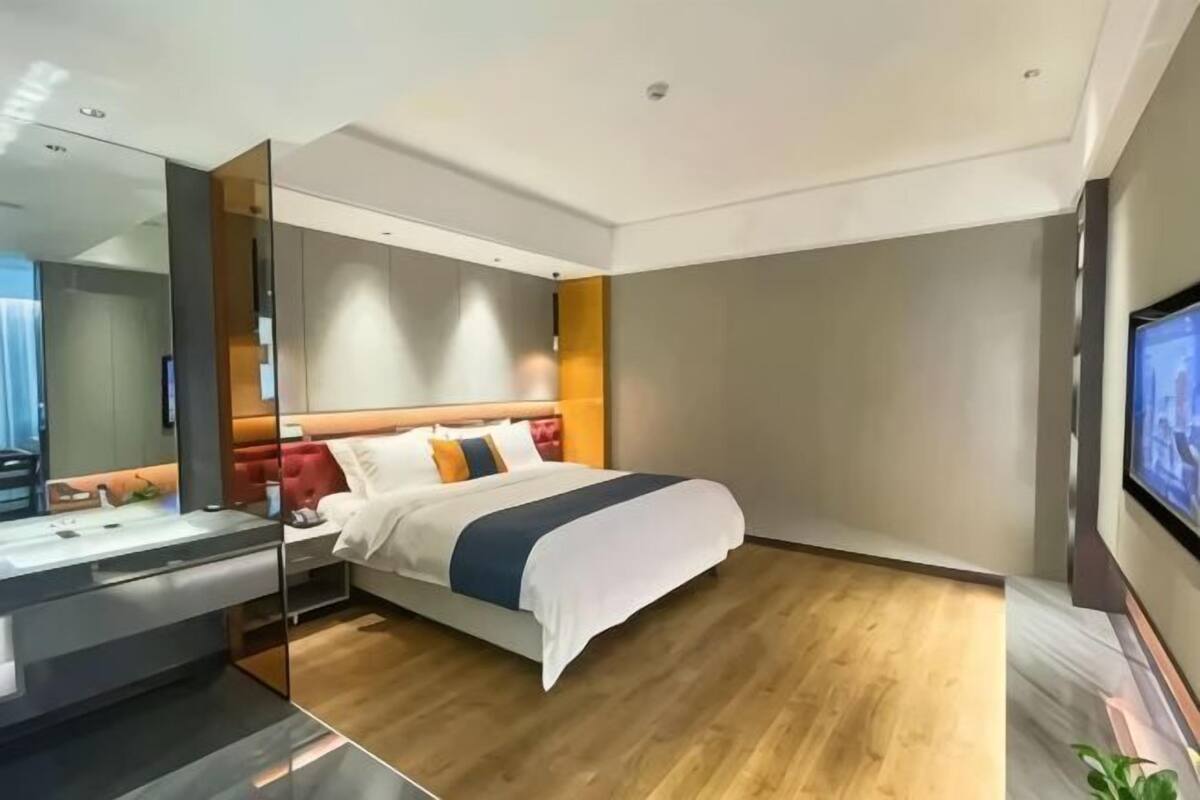 Una habitación de hotel moderna con cama, televisor, escritorio y espejo.