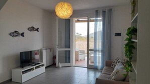 Un soggiorno moderno con una TV a schermo piatto, un mobile TV bianco e un divano con cuscini decorati.