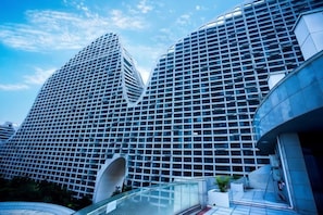 Un bâtiment moderne doté d’une façade à motifs géométriques et d’une entrée incurvée bien visible.