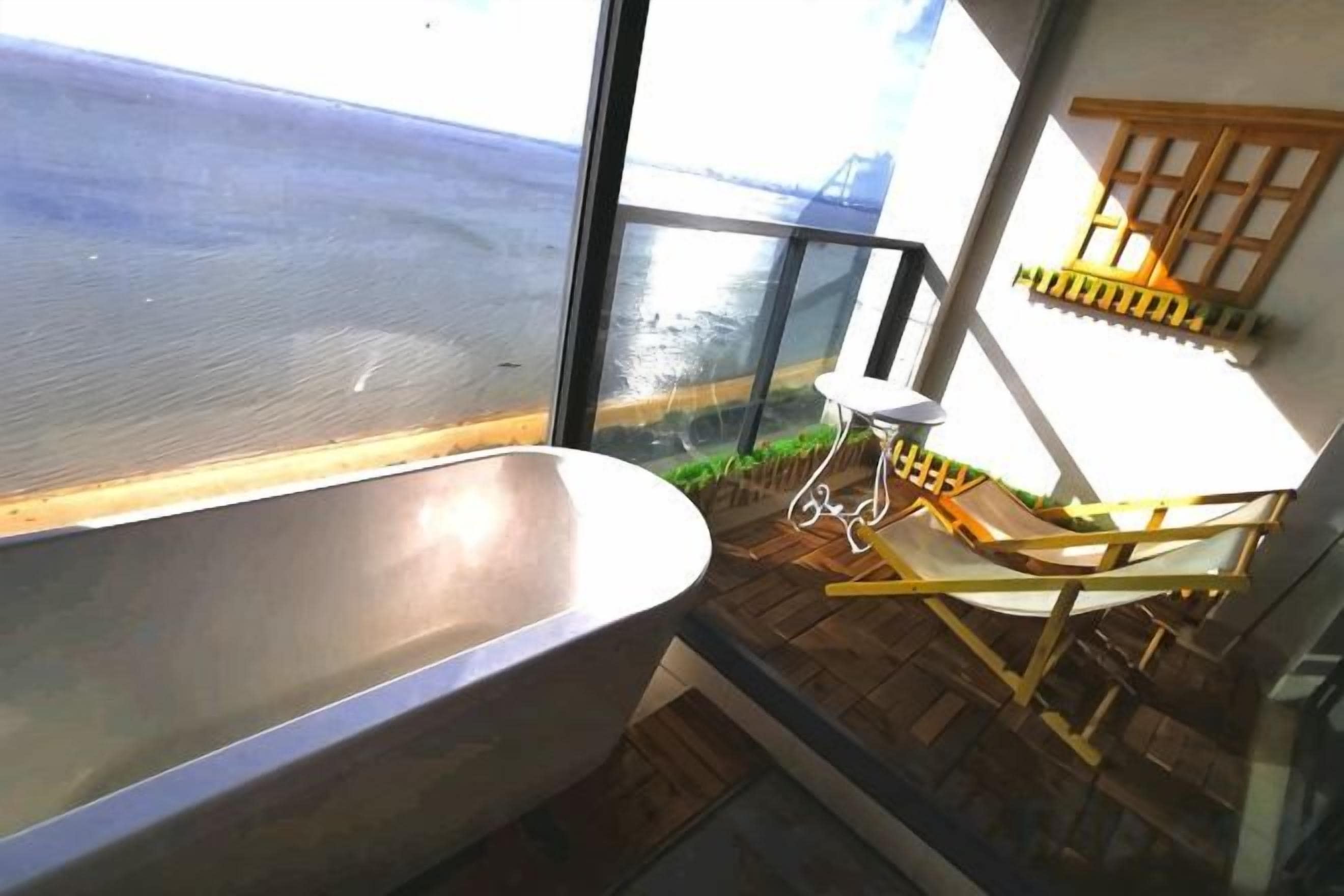 A bathtub, a wooden deck, and a view of the water.
