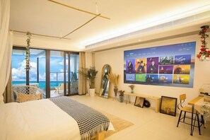 Habitación de hotel moderna con una cama grande, un balcón con vistas, un televisor montado en la pared y una zona de comedor.