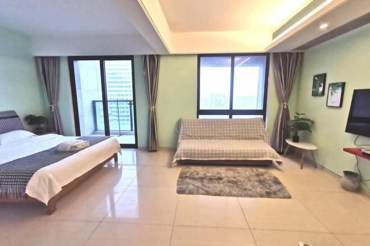 A hotel room with two beds, a TV, a small table, and a plant.