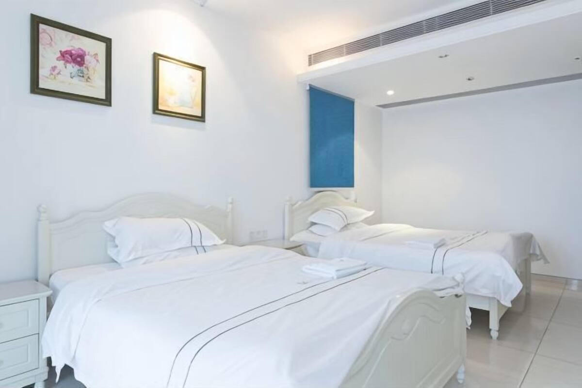 A hotel room with two beds, white bedding, a nightstand, and a framed picture on the wall.