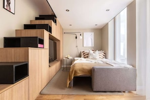 A modern bedroom with a bed, bedside table, and built-in wooden shelving unit.