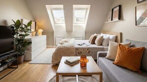 A cozy loft bedroom with a bed, a sofa, a coffee table, and a TV. - TurnKey | Angelo Roma Cozy Studio  III (Praha 2)