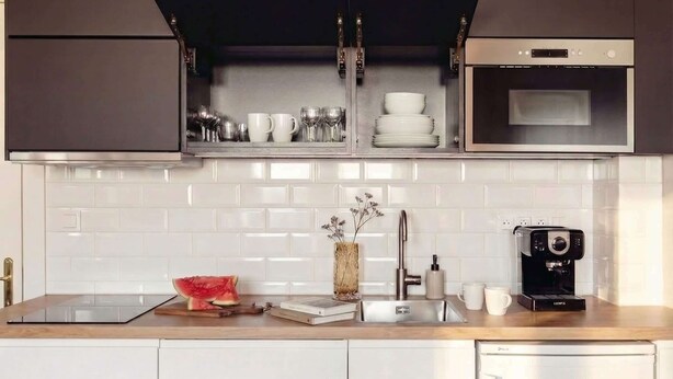A modern kitchen with a built-in oven, microwave, and a coffee machine on the counter. - TurnKey | Angelo Roma Cozy Studio  III (Praha 2)
