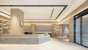A modern reception area with a marble counter, a clock, and a seating area with a television. - JI Hotel (Zhoushan Daishan Branch) (Daishan)