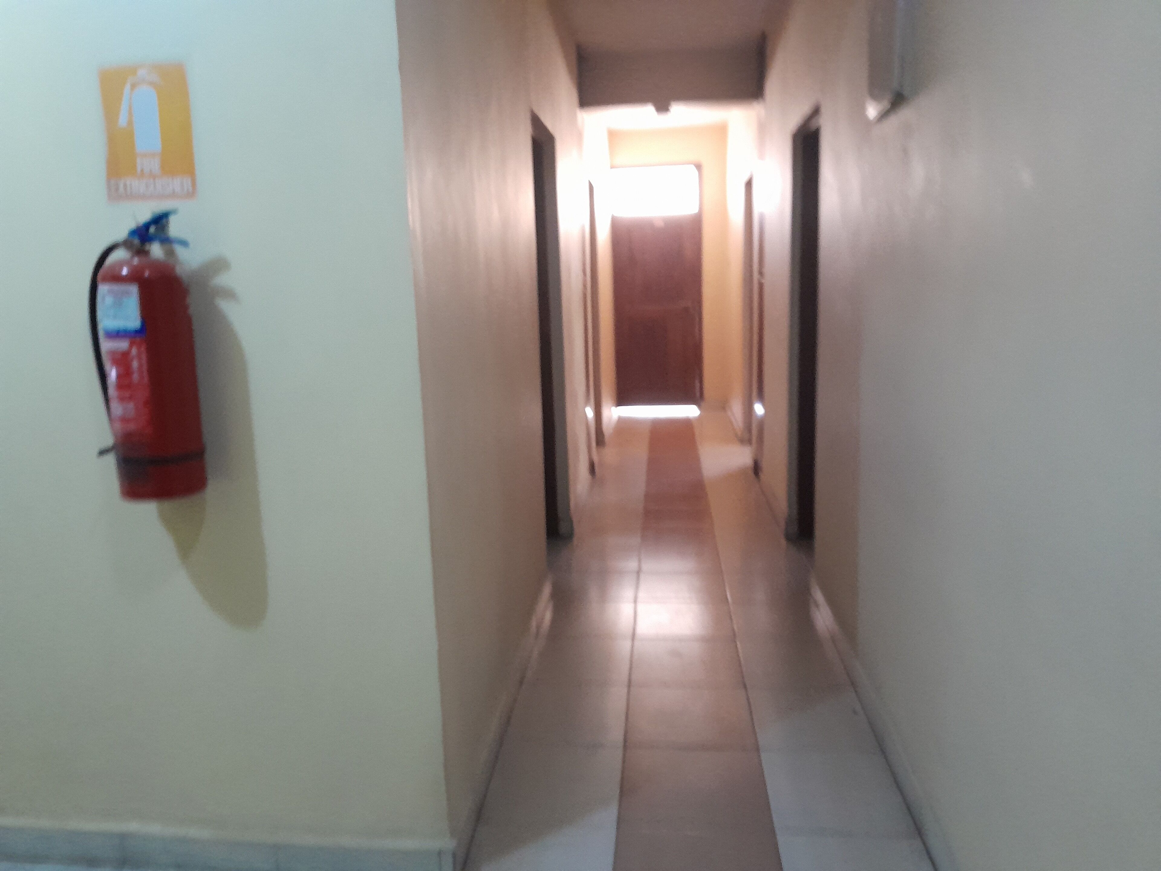 Un pasillo con un extintor montado en la pared y una puerta al final.