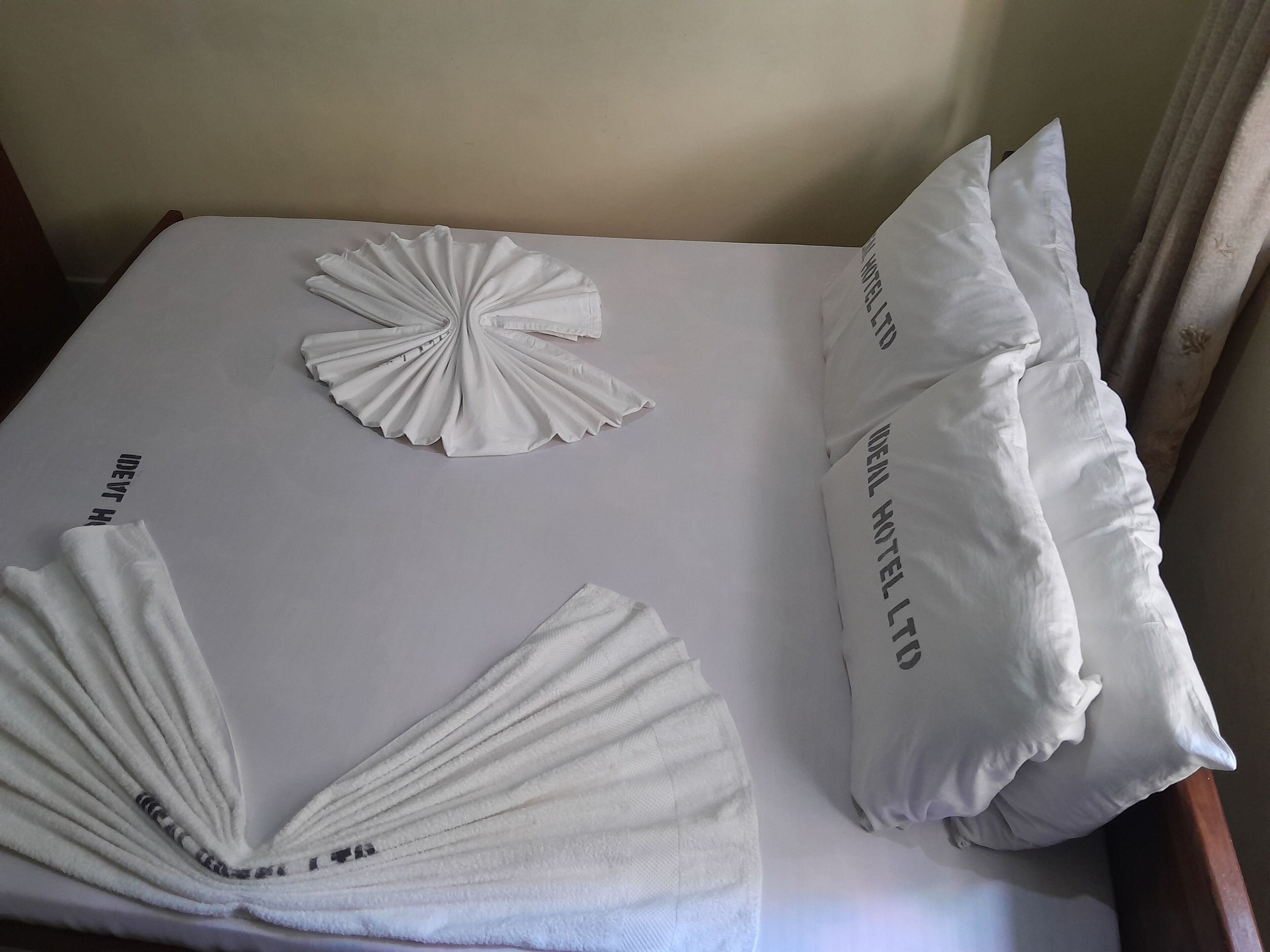 Una cama bien hecha con sábanas blancas y dos almohadas decorativas.