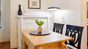 A dining area with a wooden table, chairs, a vase with a plant, a framed picture on the wall, and a floor lamp. - Black Velvet King Suite in Beautiful Highland Park (Birmingham)