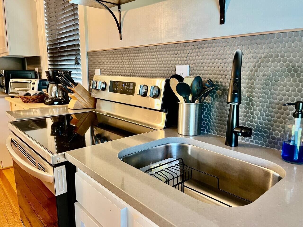 A modern kitchen with stainless steel appliances, a double sink, and a backsplash with a textured pattern.