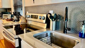 A modern kitchen with stainless steel appliances, a double sink, and a backsplash with a textured pattern.