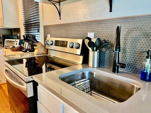 Eine moderne Küche mit Edelstahlgeräten, einer Spüle mit zwei Becken und einer Spritzschutzwand mit strukturierter Musterung.