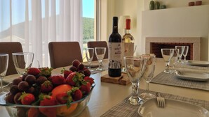 Una mesa de comedor dispuesta con copas de vino, un frutero y botellas de vino.