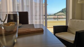 Un comedor con mesa, sillas y vistas a un balcón con edificios y vegetación.