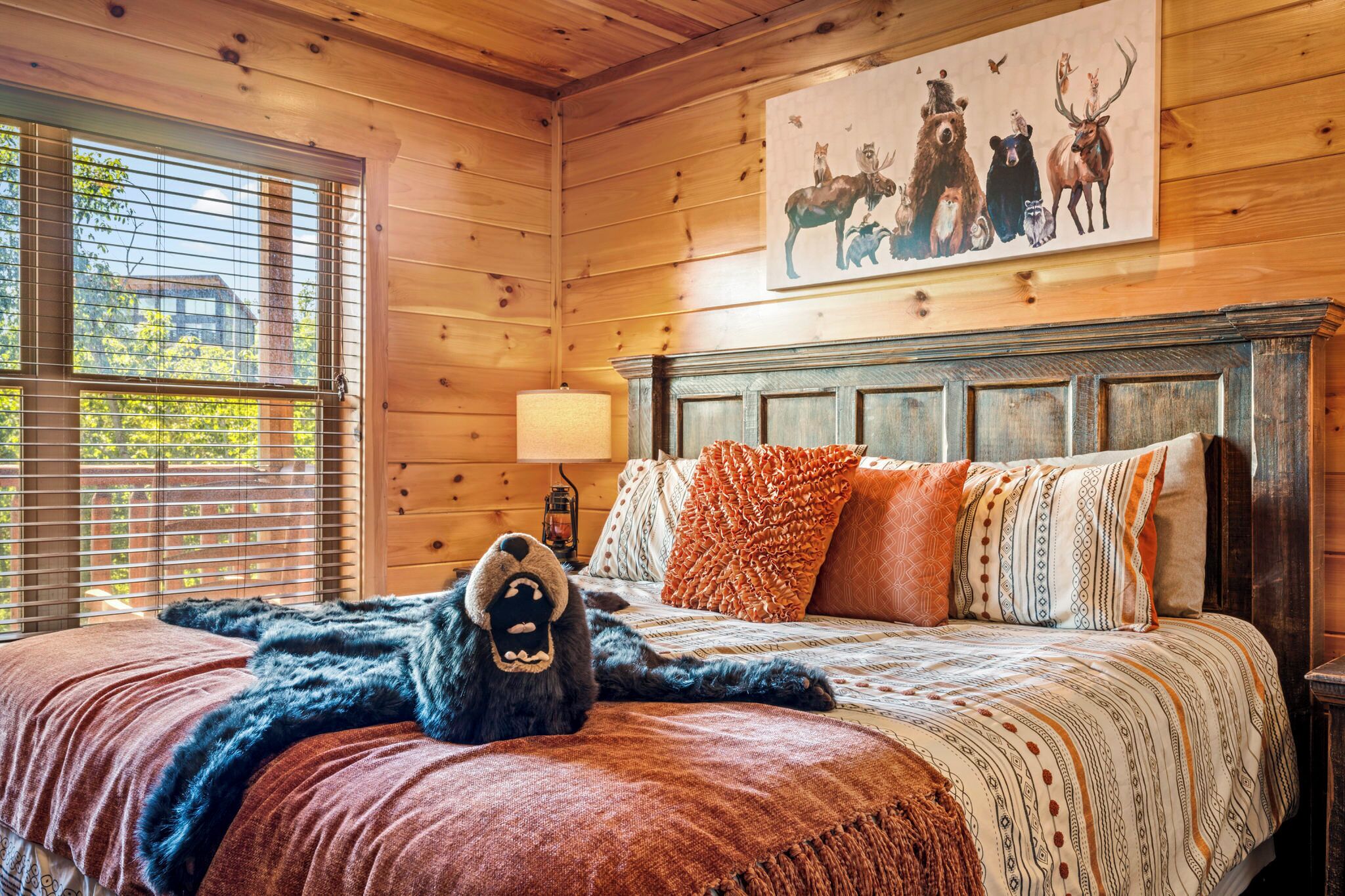 Una habitación de cabaña de madera con una cama, una lámpara y un cuadro de animales en la pared.