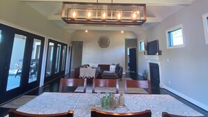 A spacious dining area with a large table, multiple chairs, and a modern chandelier.