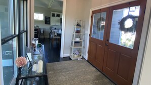 A hallway with a patterned rug, a glass table with candles, a decorative wreath, and a wooden door.