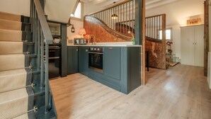 Une cuisine moderne dotée d’un four encastré, d’un escalier en bois et offrant une vue sur l’espace de vie.