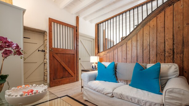 Un salon avec un canapé, une table basse en verre et un escalier en bois.