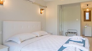 Una camera da letto con un letto grande, un comodino, un condizionatore d'aria e un bagno visibile attraverso una porta aperta.