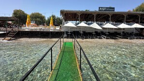 Un ristorante sulla spiaggia con posti a sedere all'aperto e una piscina trasparente.