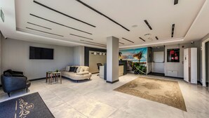 A modern hotel lobby with a reception desk, seating area, and a large TV screen. - AirGate Airport Hotel (Arnavutköy)