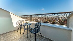 A balcony with a geometric metal railing, two chairs, and a small table with a potted plant. - AirGate Airport Hotel (Arnavutköy)