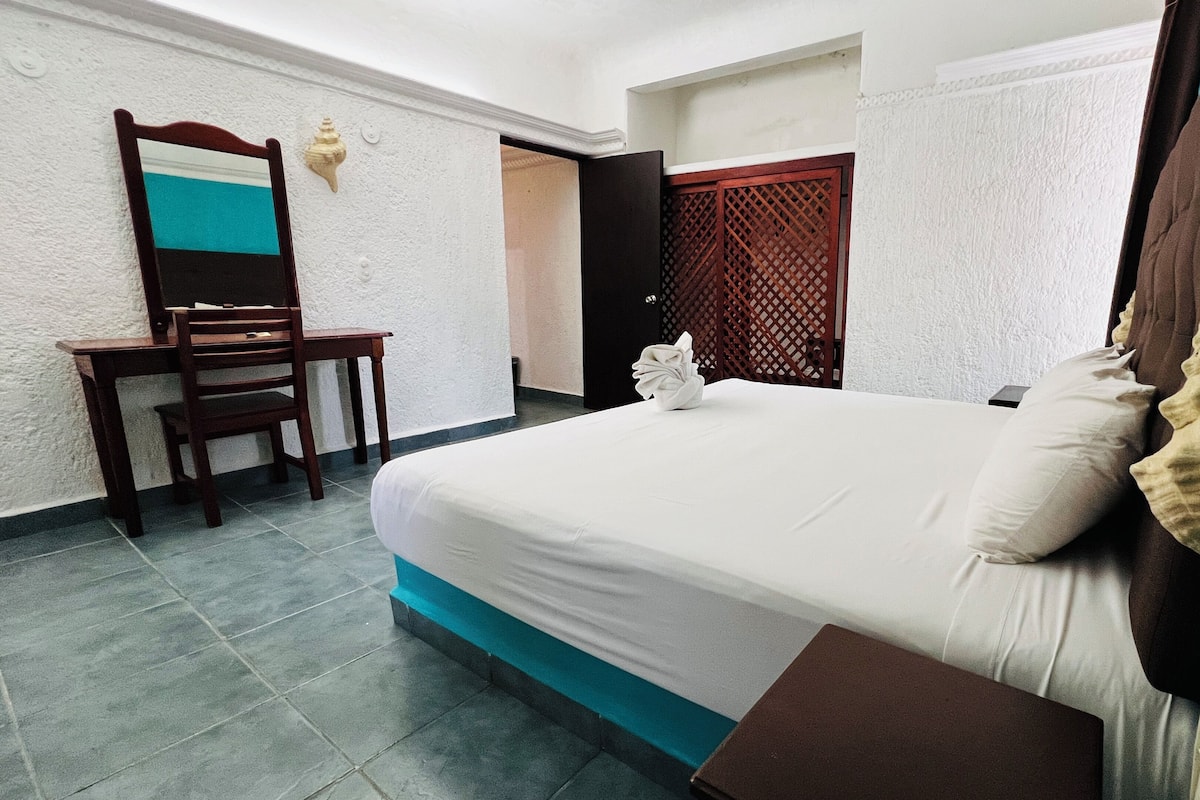 Une chambre d’hôtel avec un lit, un bureau et une chaise.