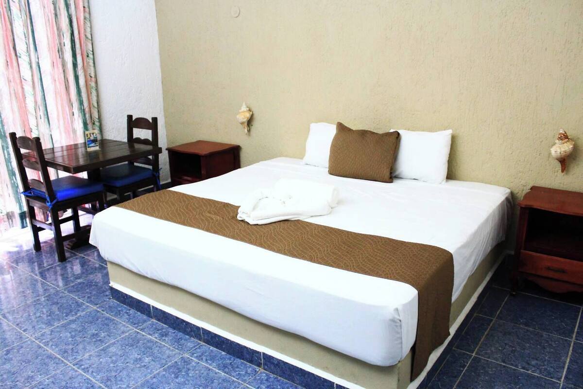 Une chambre d’hôtel avec un grand lit, un bureau en bois et une chaise.
